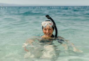 Donna allegra che indossa maschera subacquea e boccaglio sorridente nell'isola di Orange Bay a Hurghada