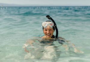 Cheerful woman wearing diving mask and snorkel smiling in Orange Bay Island in Hurghada