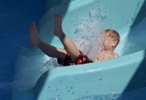 Малыш веселится в аквапарке летом