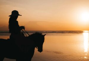 Silhouette of young woman riding on a horseback