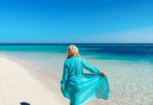 девушка гуляет по белому песку вдоль бирюзового моря на острове Парадайз в Египте