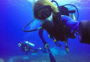 Underwater scuba diving selfie shot with selfie stick. Deep blue sea. Wide angle shot.