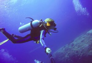 Underwater scuba diving selfie shot with selfie stick. Deep blue sea. Wide angle shot.
