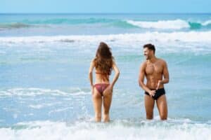 Young couple bathing together on the beach enjoying their holiday at sea