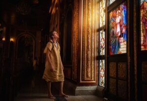 young man tourist stands at painted window in Coptic church in Egypt, looking at the falling light