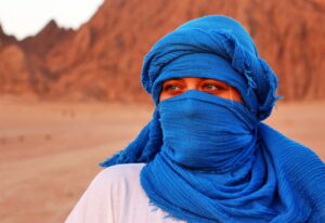 A millennial girl wearing a blue desert scarf during a desert tour