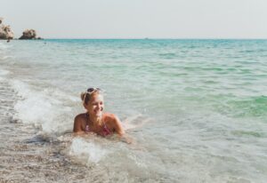 A young woman lies on the seashore and rejoices in the waves. Vacation and travel concept