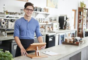 Male coffee shop owner behind the counter at his coffee shop