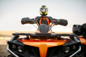 Rider in helmet on quad bike, front view, closeup