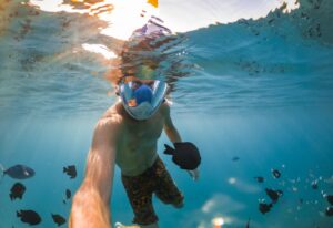 Snorkeling near a tropical island. Young man swims in the water. Sea vacation