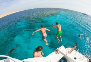 Two men jump into the sea from a yacht. Friends are having fun on vacation.