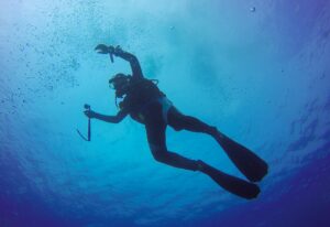 Underwater scuba diving selfie shot with selfie stick. Deep blue sea. Wide angle shot.
