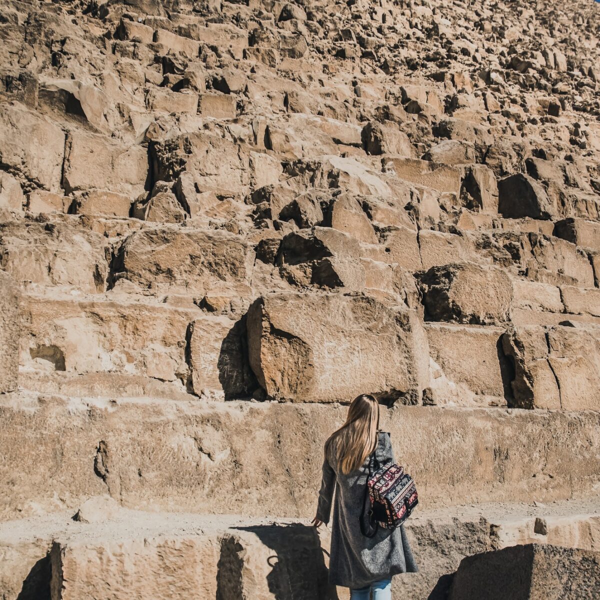 En europæisk blondine går i nærheden af pyramiderne i ørkenen i Kairo