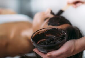 Bella giovane donna che ha una maschera per il viso al cioccolato