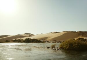 Scenic View Of Nile River By Sand Dune Against Clear Sky At Aswan On Sunny Day